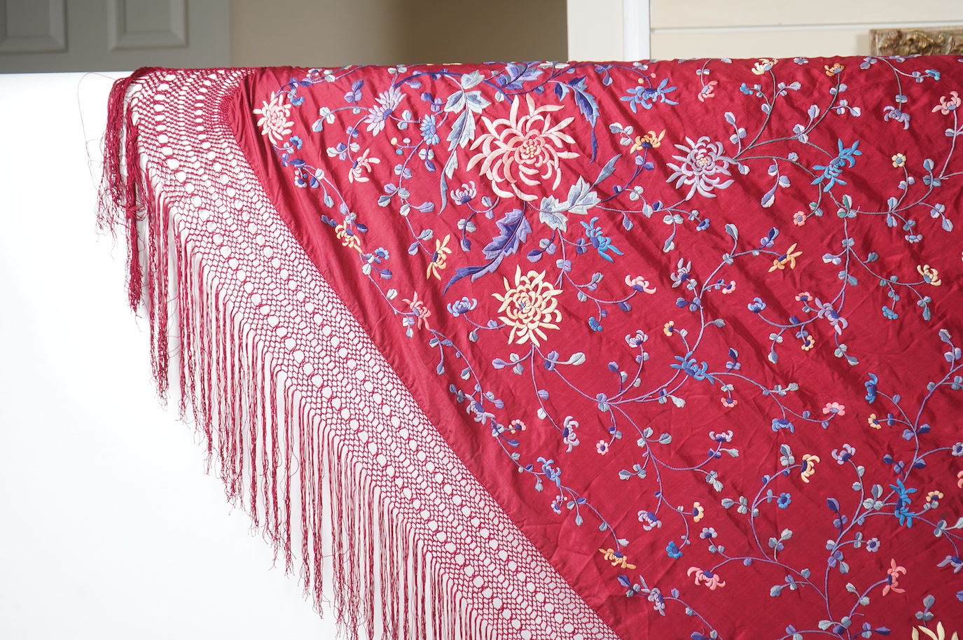 A late 19th early 20th century Chinese silk polychrome embroidered shawl on a maroon silk background. Fringed. 180cm x 60cm. Condition - no fading to colours, silk good